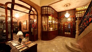 A lobby with a reception desk, a staircase, and a chandelier. - Hotel Nouvel (Barcelona)