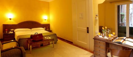 A hotel room with a bed, bedside tables, a desk with a chair, a bench, and a window with a view.