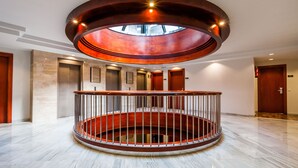 A spacious lobby with a central circular staircase, multiple elevators, and a skylight above. - Hotel VM Prisma (Escaldes-Engordany)