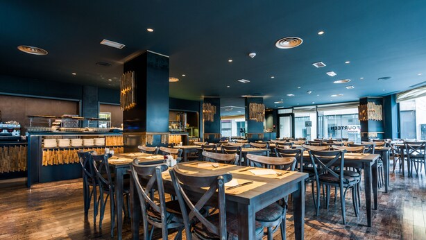 A spacious restaurant with multiple tables and chairs, a bar area, and a view of the cityscape through large windows. - Hotel VM Prisma (Escaldes-Engordany)