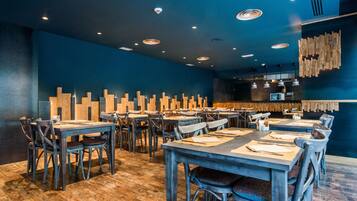 A restaurant with wooden tables and chairs, a blue wall, and a wooden wall decoration.