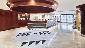 A modern hotel lobby with a central reception desk, a polished marble floor, and a large circular ceiling feature. - Hotel VM Prisma (Escaldes-Engordany)