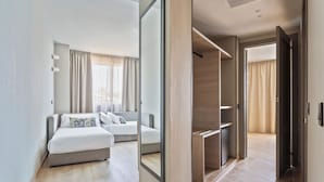Een moderne hotelkamer met een groot bed, een inloopkast en uitzicht op de gang.