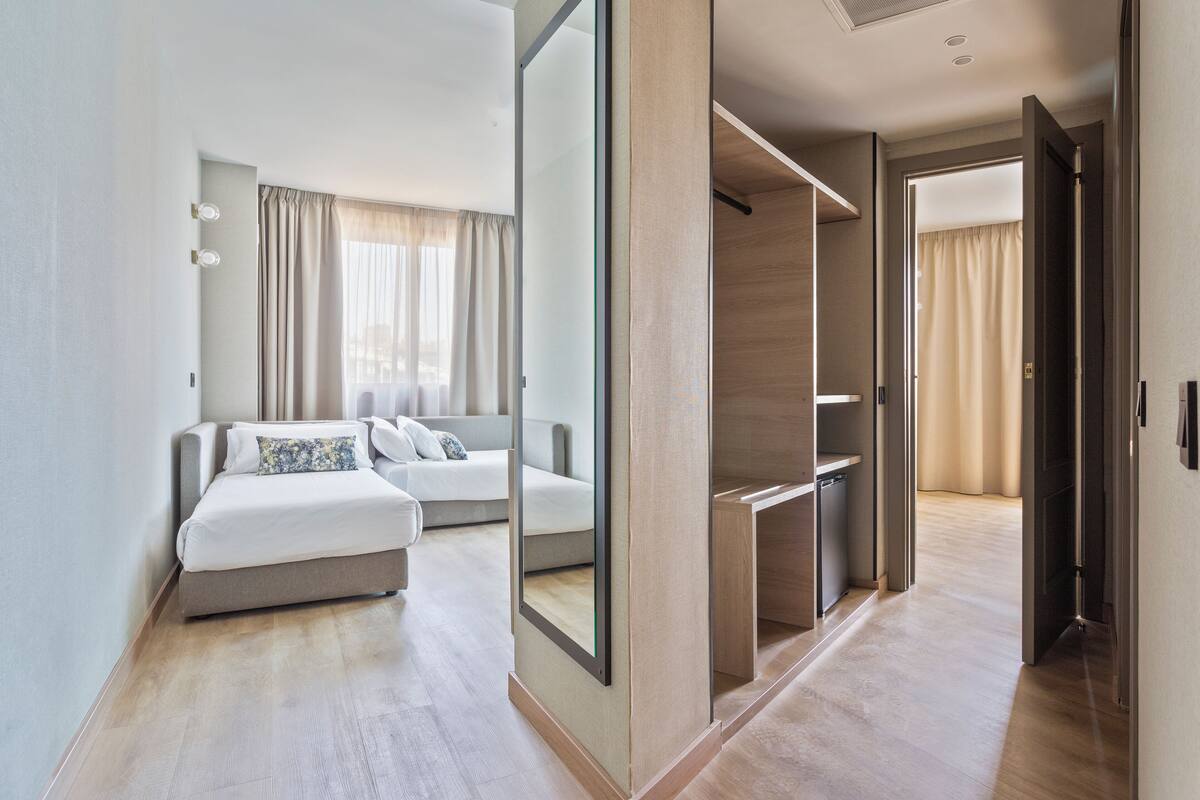 Una camera d'albergo moderna con un letto grande, una cabina armadio e vista sul corridoio.