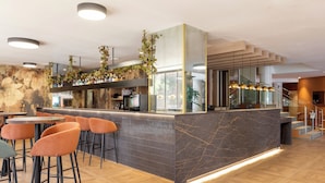 Een moderne bar met een marmeren aanrecht, meerdere barkrukken en een trap naar een hoger niveau.