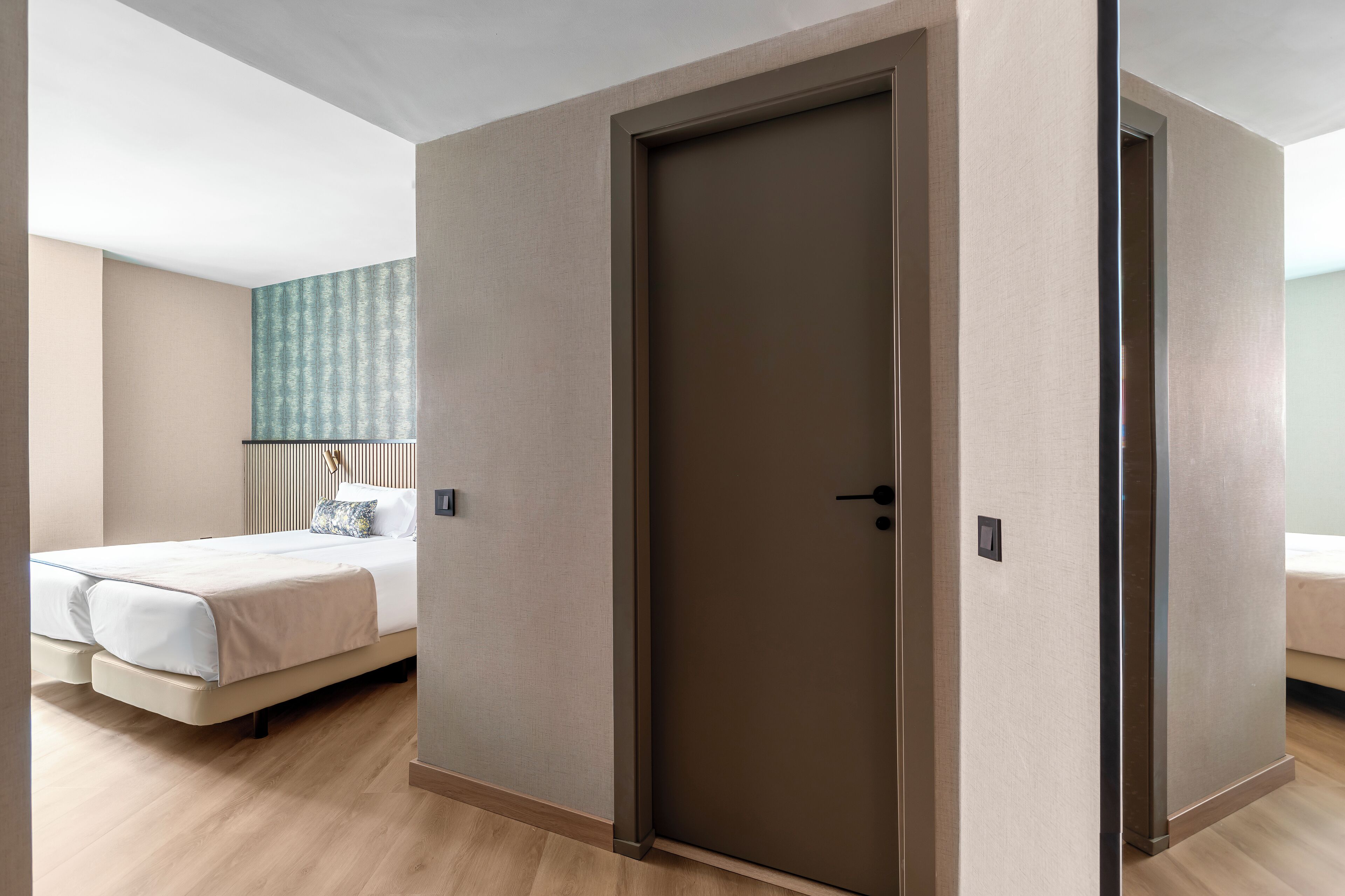 Una habitación de hotel moderna con una cama grande, una puerta y una pared con papel tapiz estampado.