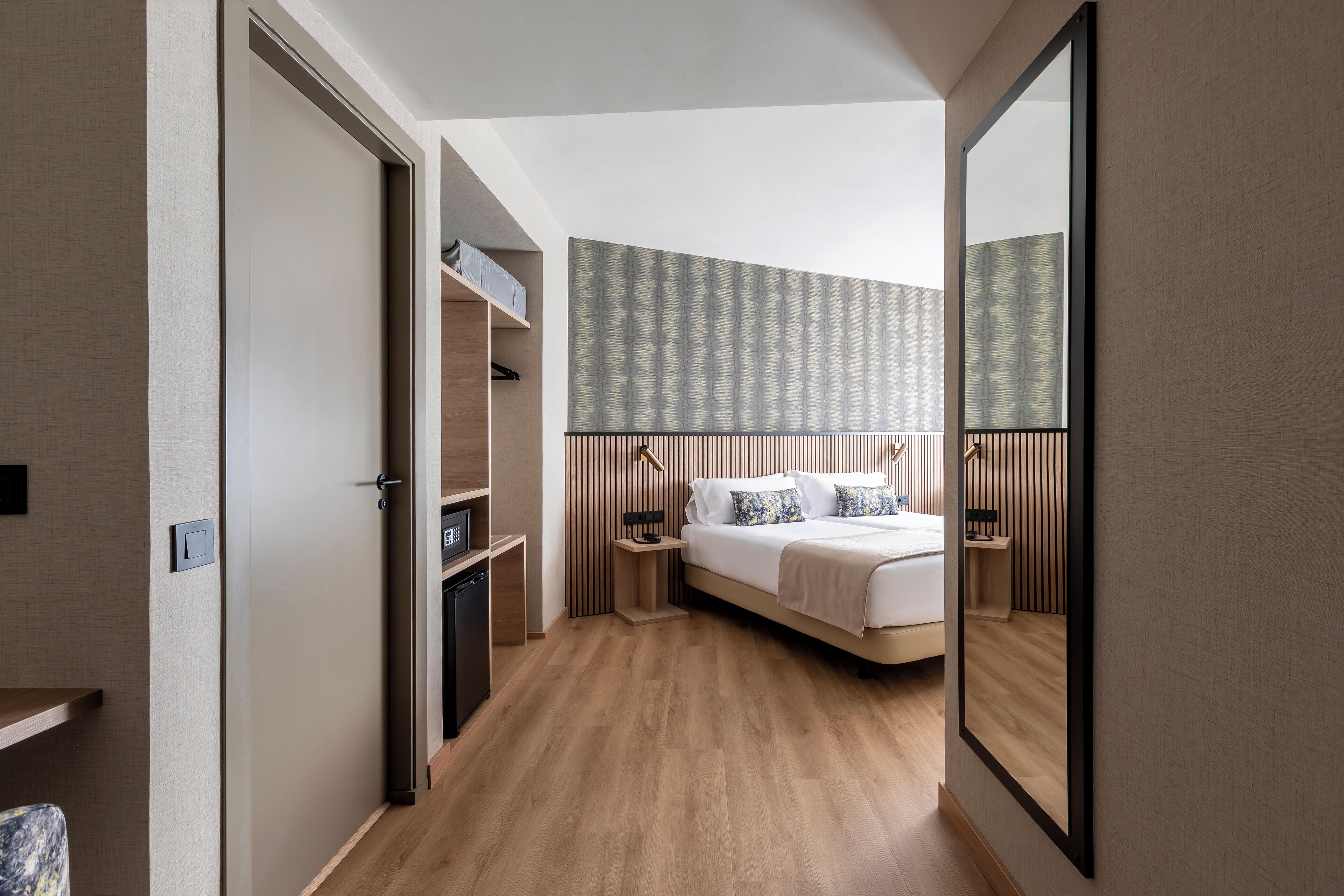 Une chambre moderne avec un plancher en bois, un lit avec une literie blanche, une table de chevet, un miroir et des étagères intégrées.