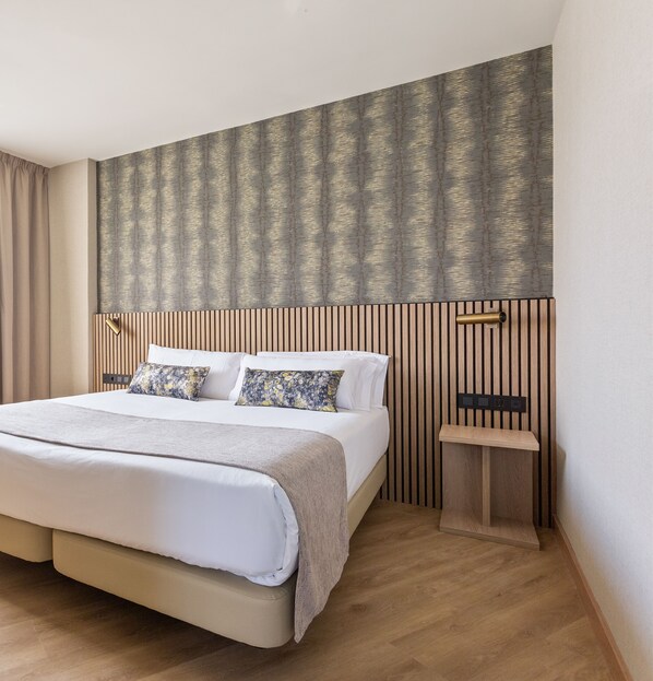 Ett modernt hotellrum med en stor säng, ett träbeklätt sänggavel och ett inbyggt nattduksbord.