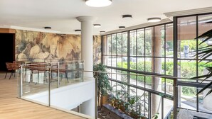 Een modern interieur met een glazen balustrade, een muurschildering en uitzicht op de omgeving.
