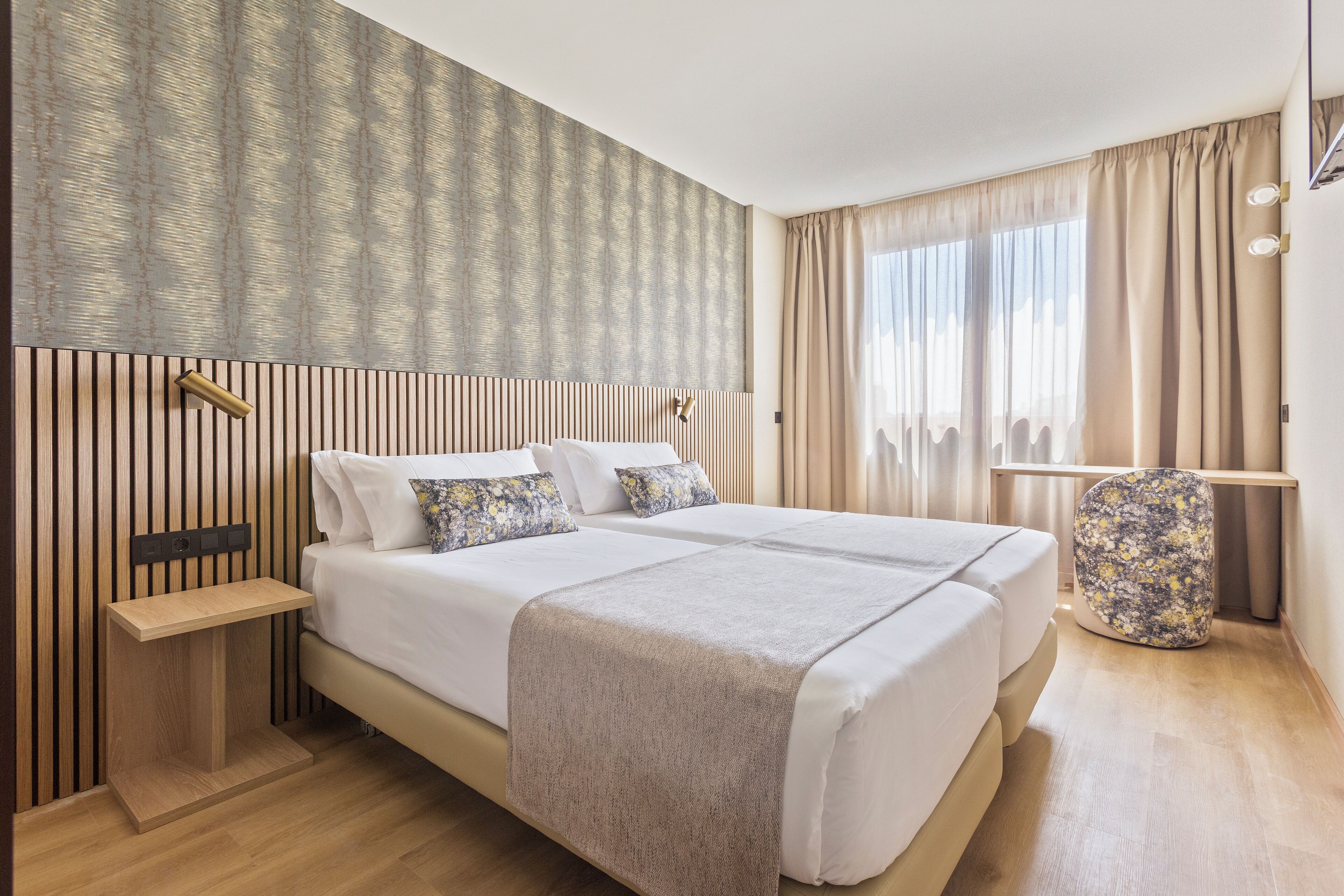 A modern hotel room with a large bed, bedside tables, and a nightstand.
