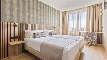 A modern hotel room with a large bed, bedside tables, and a nightstand.