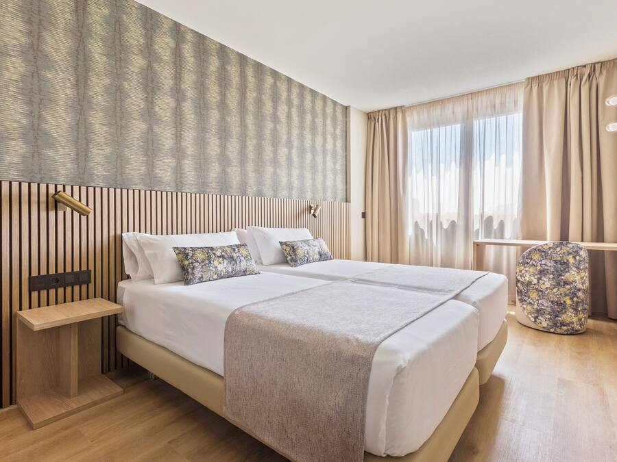 A modern hotel room with a large bed, bedside tables, and a nightstand.