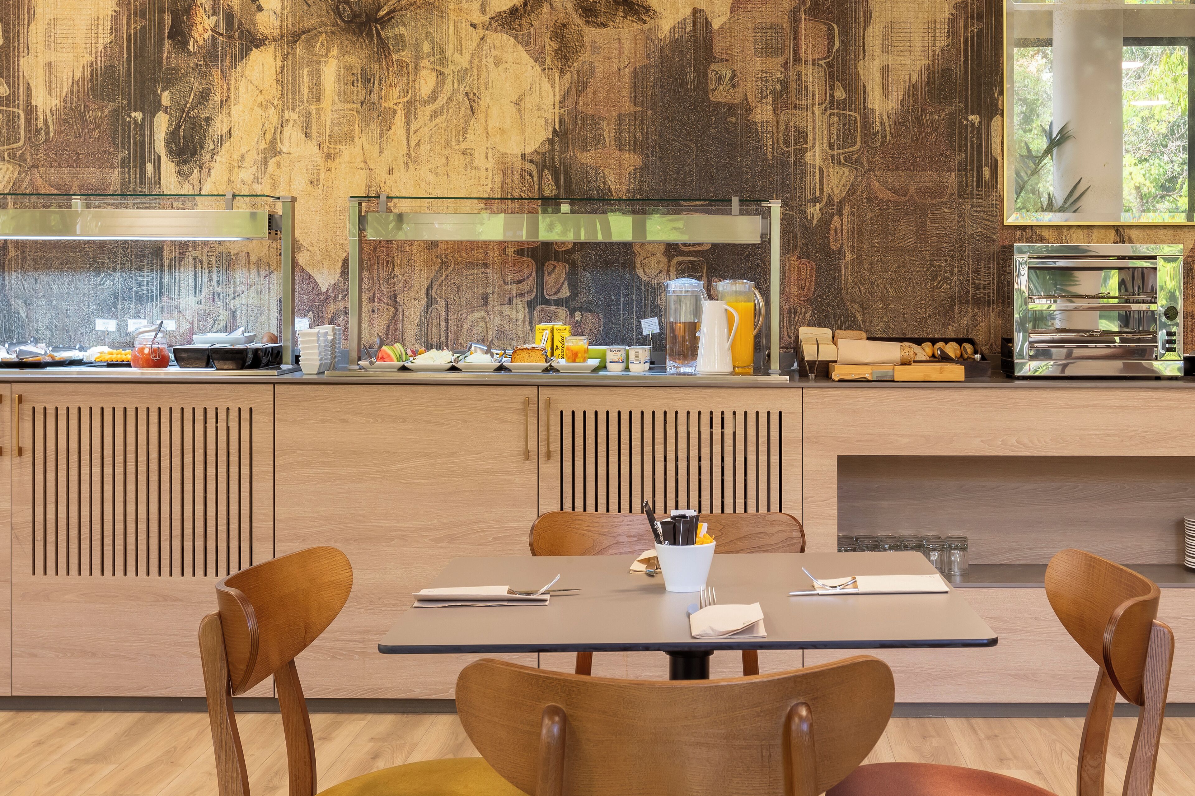 En moderne restaurant med træbeklædte vægge, et buffetbord med forskelligt mad og et siddeområde med borde og stole.