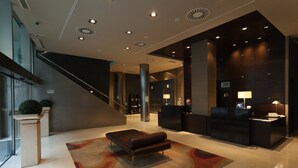 A modern lobby with a reception desk, a seating area, and a staircase. - Hotel Conqueridor (Valencia)