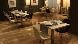 A modern dining area with multiple tables and chairs, framed artwork on the walls, and ambient lighting. - Hotel Conqueridor (Valencia)