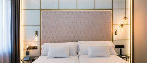 A double bed with a tufted headboard, bedside tables with lamps, and a modern light fixture.