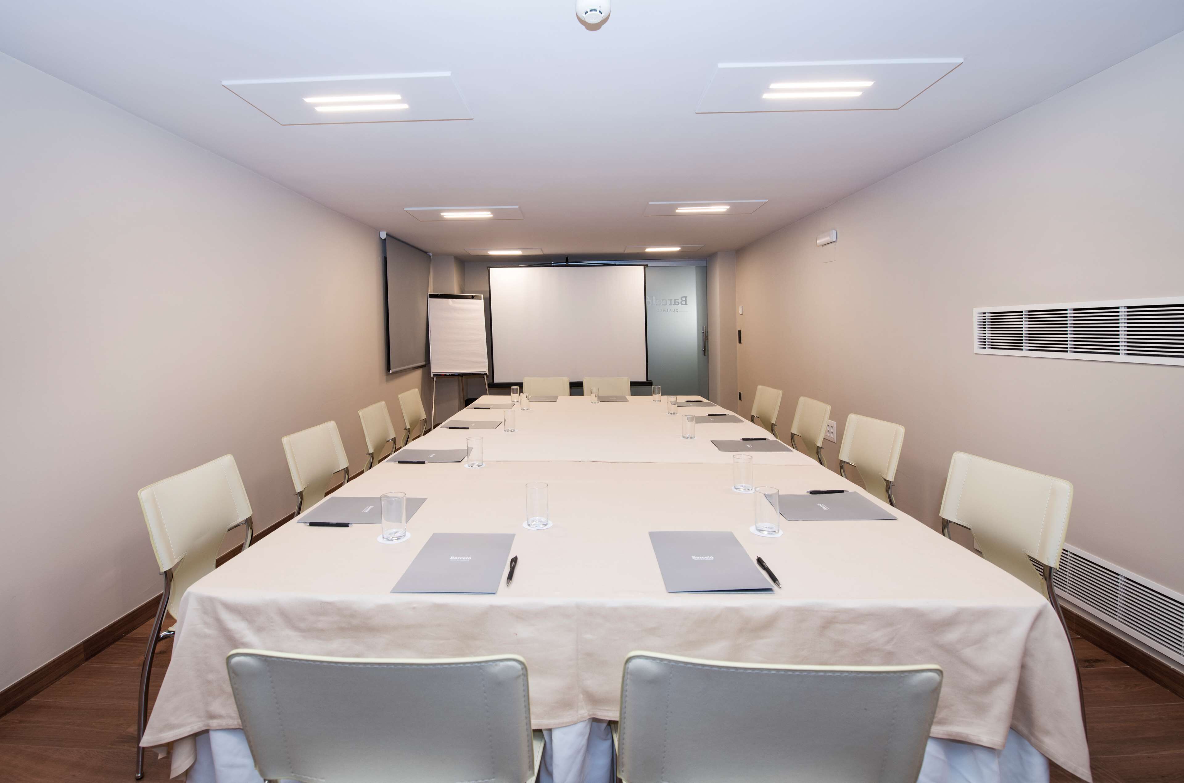 Une salle de conférence équipée d’une longue table, de chaises, d’ordinateurs portables et d’un écran de projection.