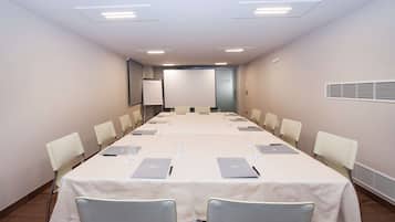 A conference room with a long table, chairs, laptops, and a projector screen.
