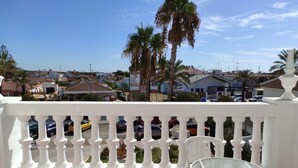 A balcony with a white balustrade, a glass table, and a white chair. - Hotel Carabela Santa Maria (Moguer)