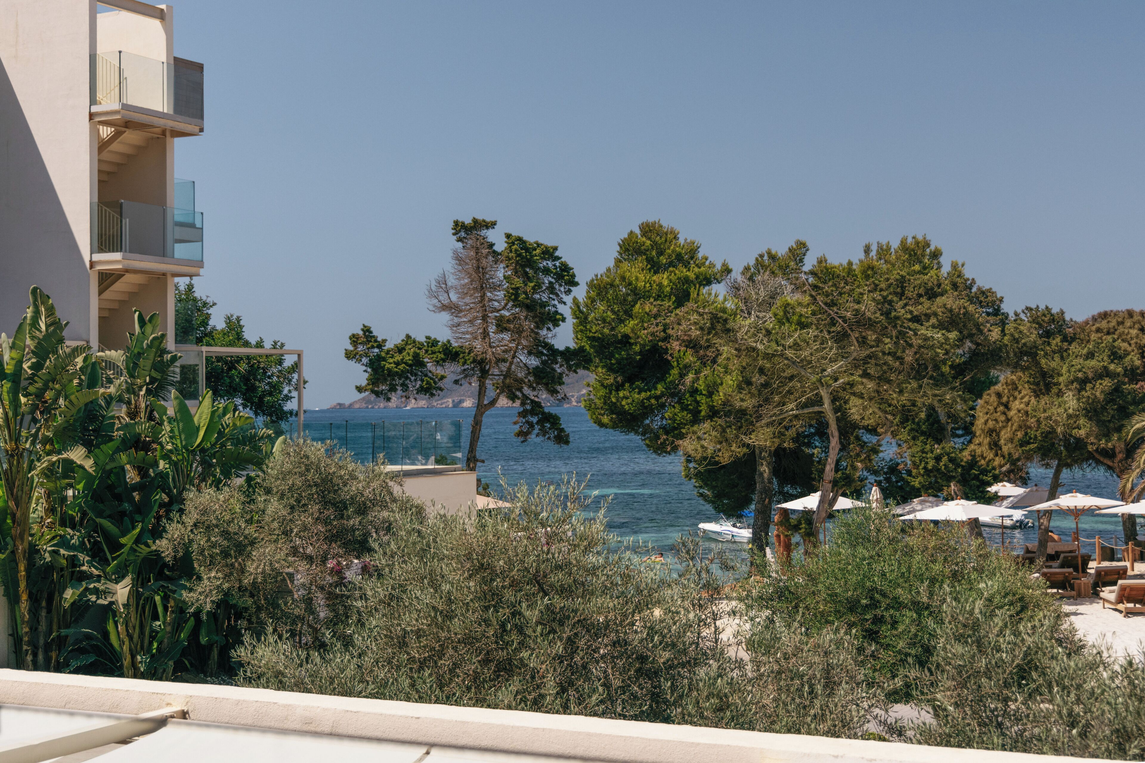 Ein Hotel an der Küste mit Poolbereich, Sitzgelegenheiten im Freien und Blick aufs Meer.