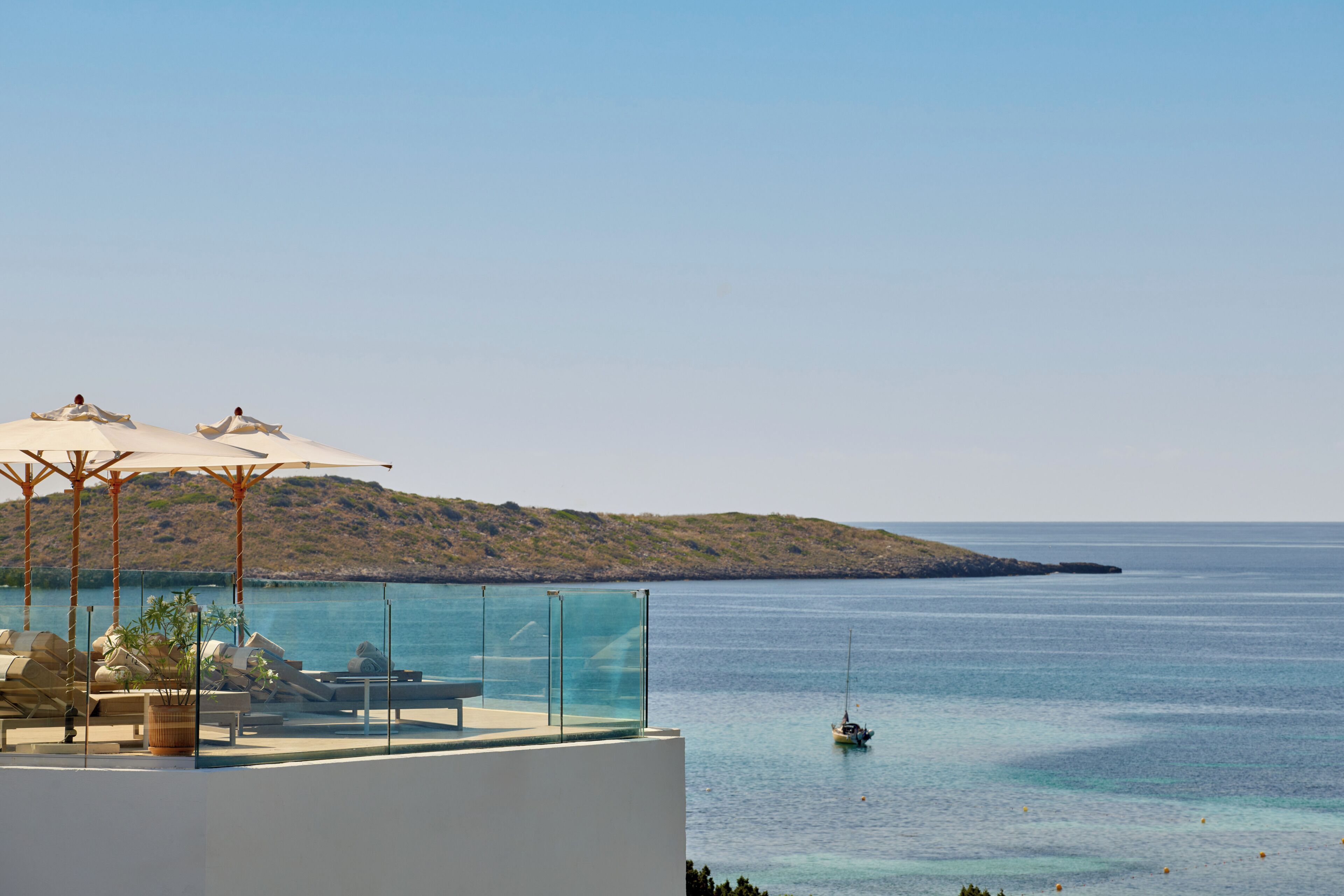 A seaside terrace with outdoor seating and umbrellas overlooking the sea.