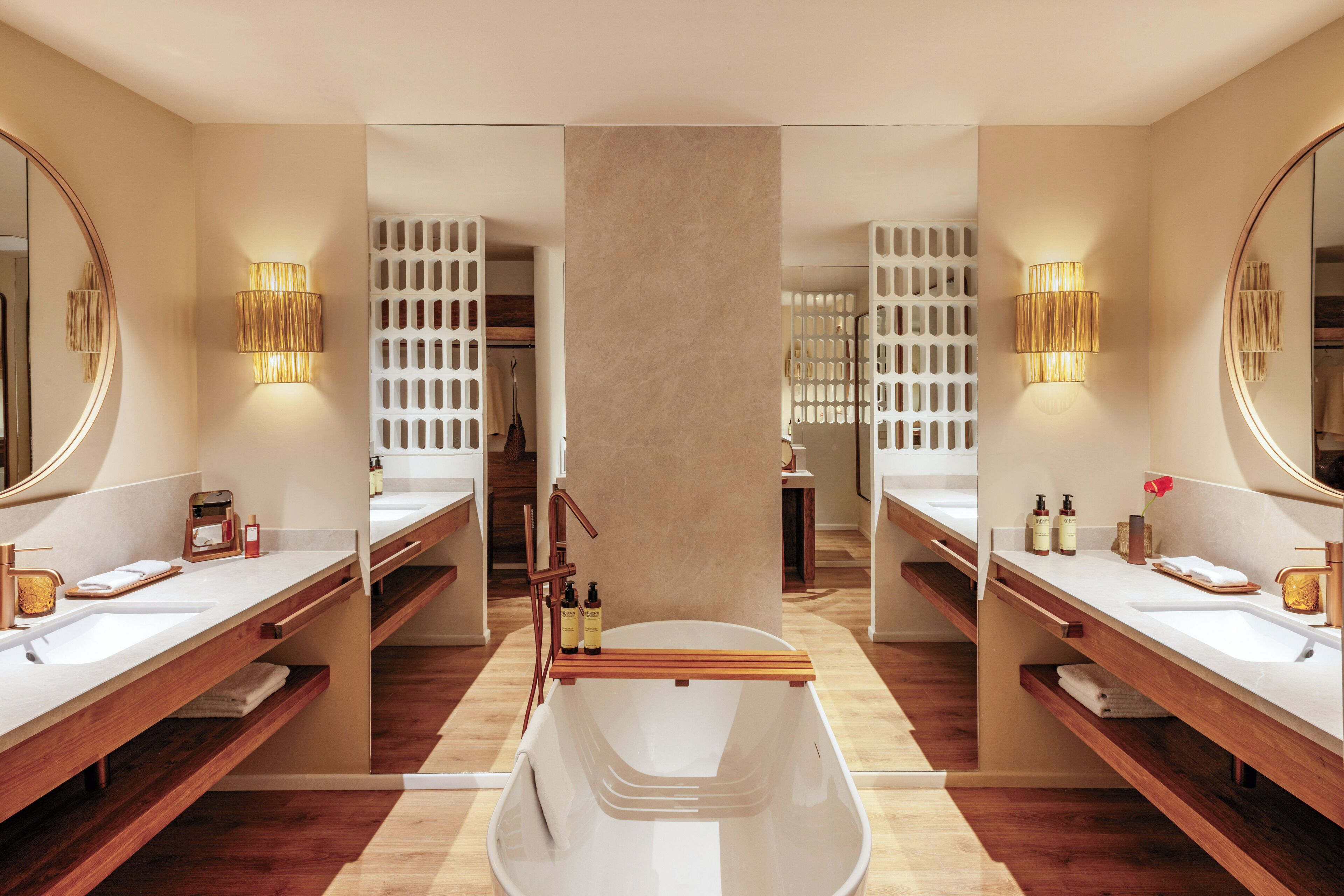 A modern bathroom with two sinks, a bathtub, and a mirror.