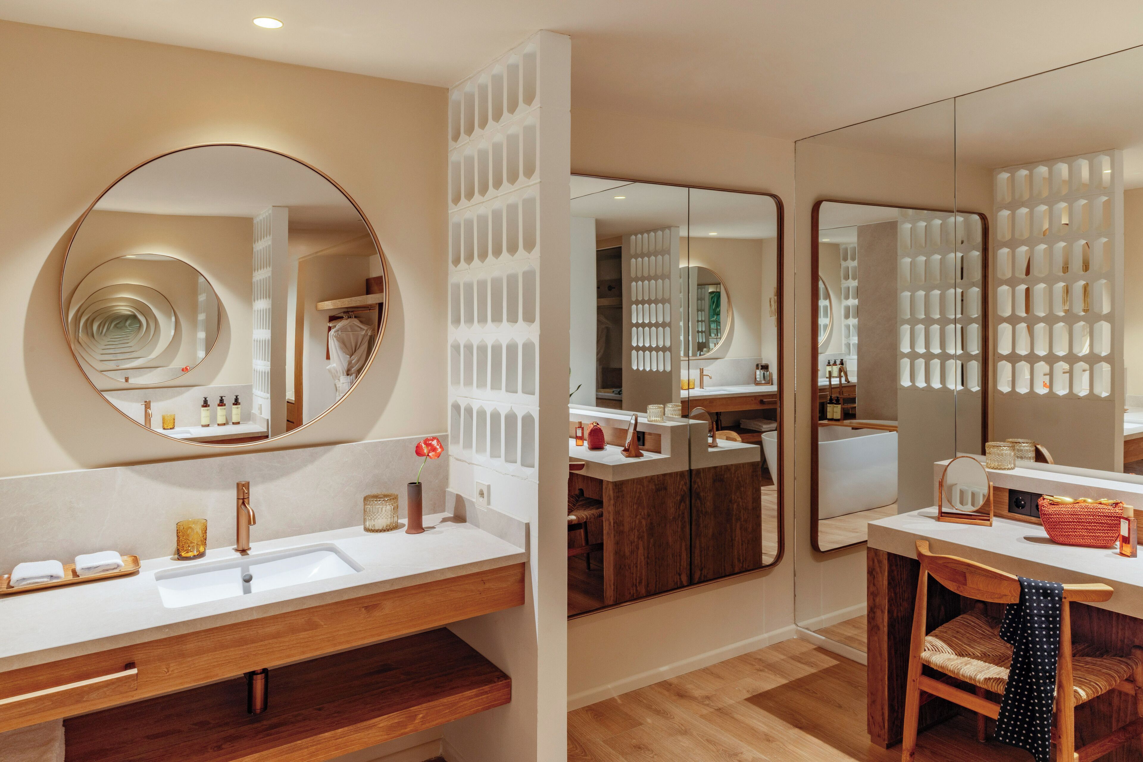 Un baño moderno con un espejo grande, un tocador de madera y un área separada para el lavamanos.