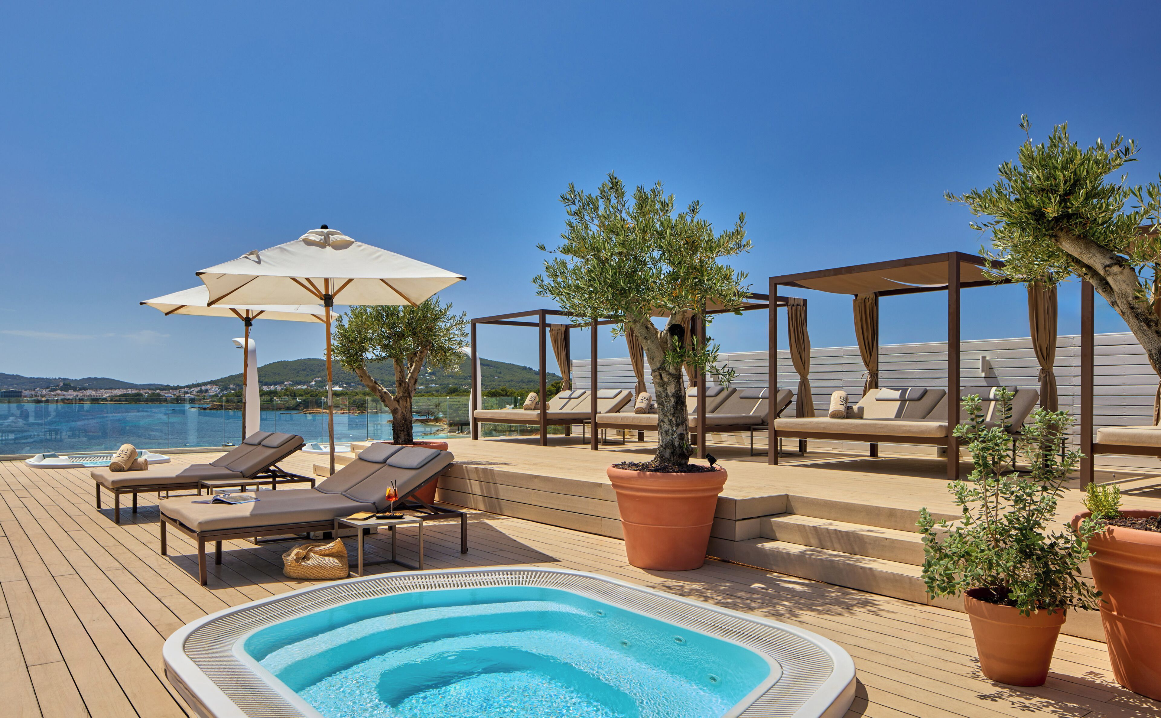 Ein Poolbereich mit Liegestühlen, einem Whirlpool und Blumentöpfen.