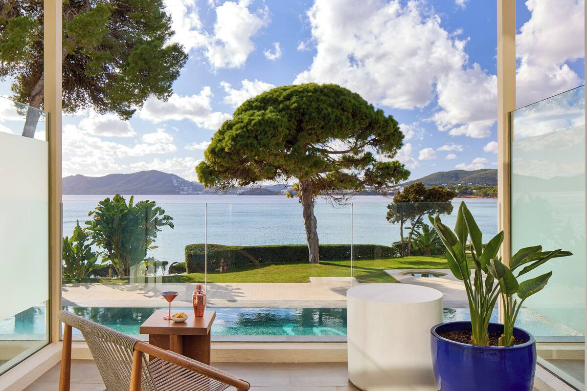 A balcony with a view of a lake, a swimming pool, and a well-maintained lawn.