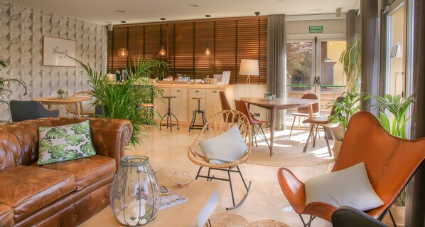Un moderno vestíbulo de hotel con sofás de cuero, sillas de mimbre y una zona de bar central.