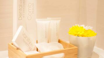 A wooden tray with various toiletries including a dental kit, comb, shampoo, shower gel, and a vanity set.