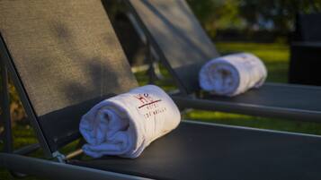 A lounge chair with a rolled-up towel on it.