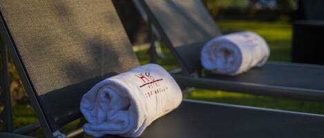 A lounge chair with a rolled-up towel on it.