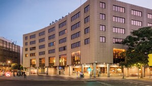 Ein mehrgeschossiges Hotel mit modernem Design, das durch einen markanten Eingangsbereich mit beleuchteter Beschilderung besticht.