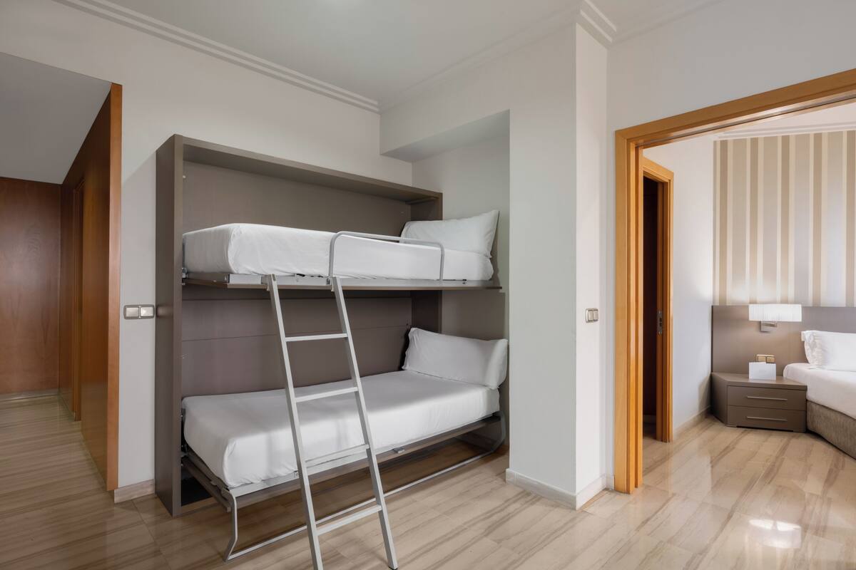 Een stapelbed met een ladder, een nachtkastje en een nachttafeltje.