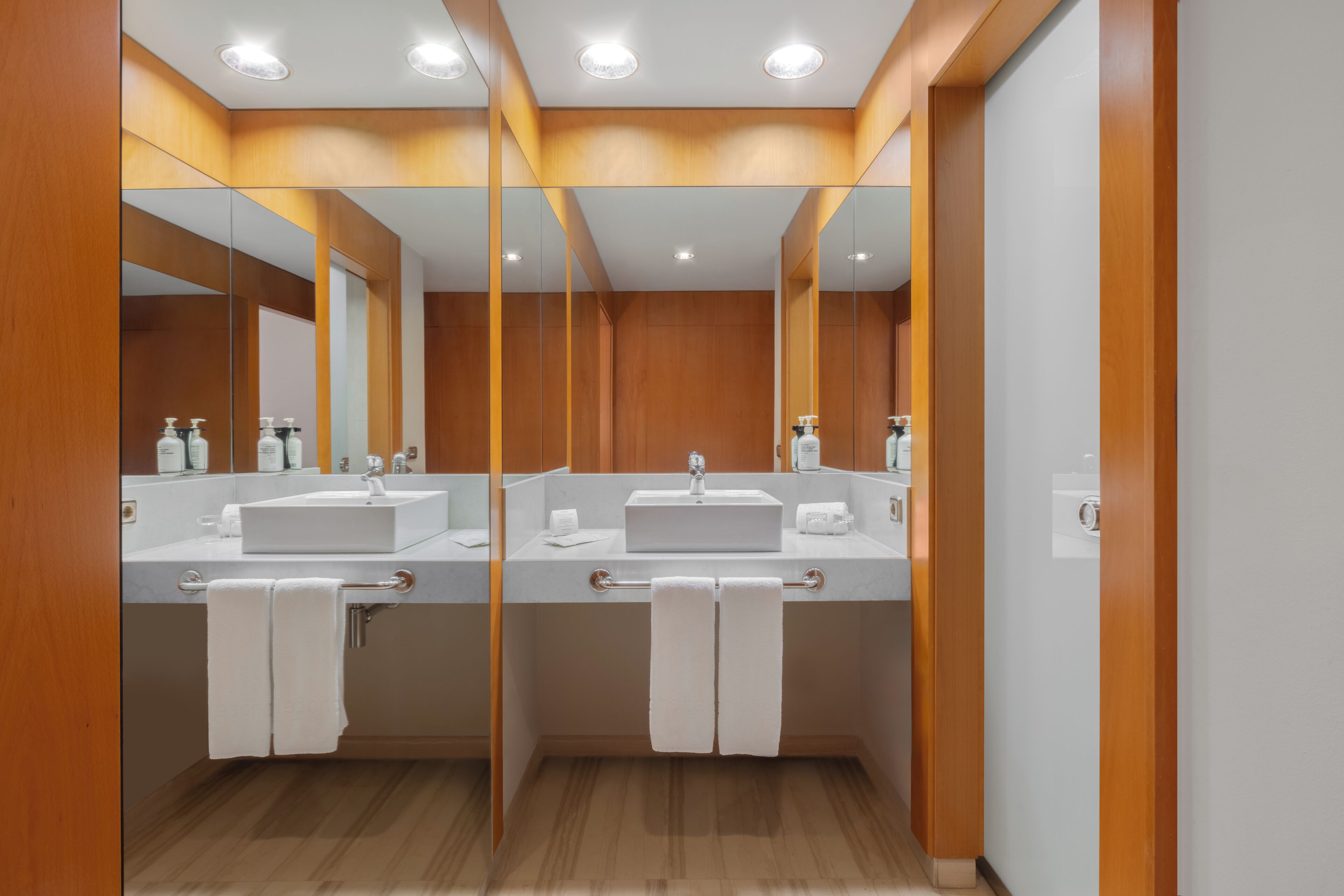 A modern bathroom with two sinks, mirrors, and wooden paneling.