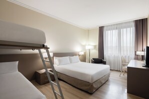 Ein Hotelzimmer mit Etagenbett, Schreibtisch, Stuhl, Lampe und Fernseher.