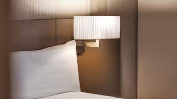 A hotel room with a bed, a nightstand, a lamp, and a book on the bed.
