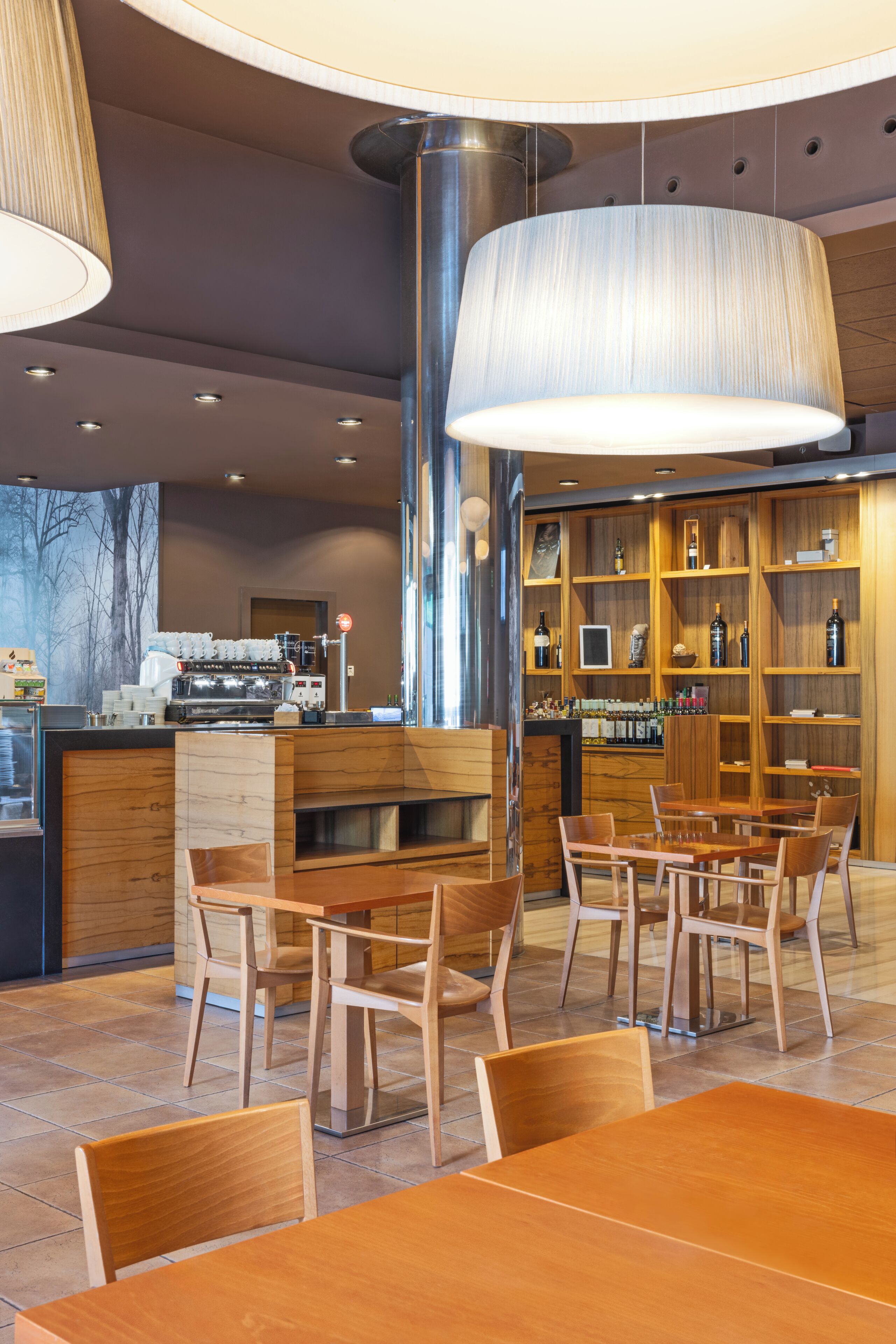 Un interior de cafetería moderno con mobiliario de madera, una barra de café y una vitrina con vinos.