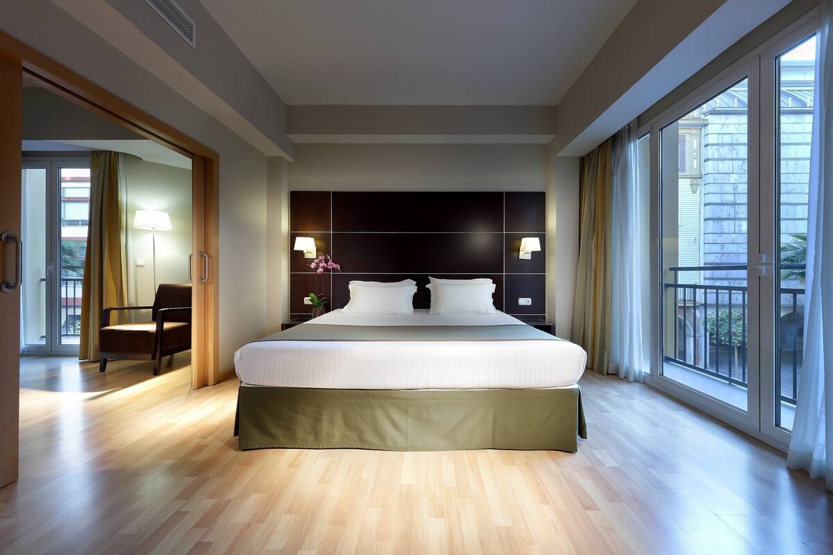 Une chambre d’hôtel moderne, dotée d’un grand lit, d’une chaise, d’un bureau et d’un balcon avec vue.