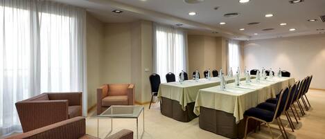 Sala de conferências com uma mesa comprida, cadeiras e um espaço de estar pequeno.
