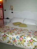 A bed with a floral bedspread, a bedside lamp, and a nightstand with a phone.