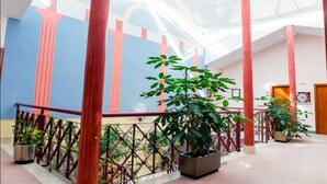 A spacious atrium with a high ceiling, red columns, and potted plants. - Hotel Velada Mérida (Merida)