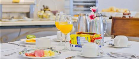 Una mesa de desayuno con platos de comida, vasos de zumo de naranja y una jarra de agua.