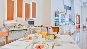 A breakfast buffet setup with a variety of food items, a coffee machine, and a juice dispenser. - Hotel Velada Mérida (Merida)