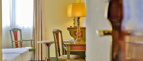 A hotel room with a bed, two chairs, a small table, and a lamp.