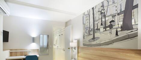 Une chambre d’hôtel avec un lit, un bureau et une chaise, un tableau au mur et une fenêtre.