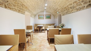 Comedor con techo de piedra, mesas y sillas de madera.