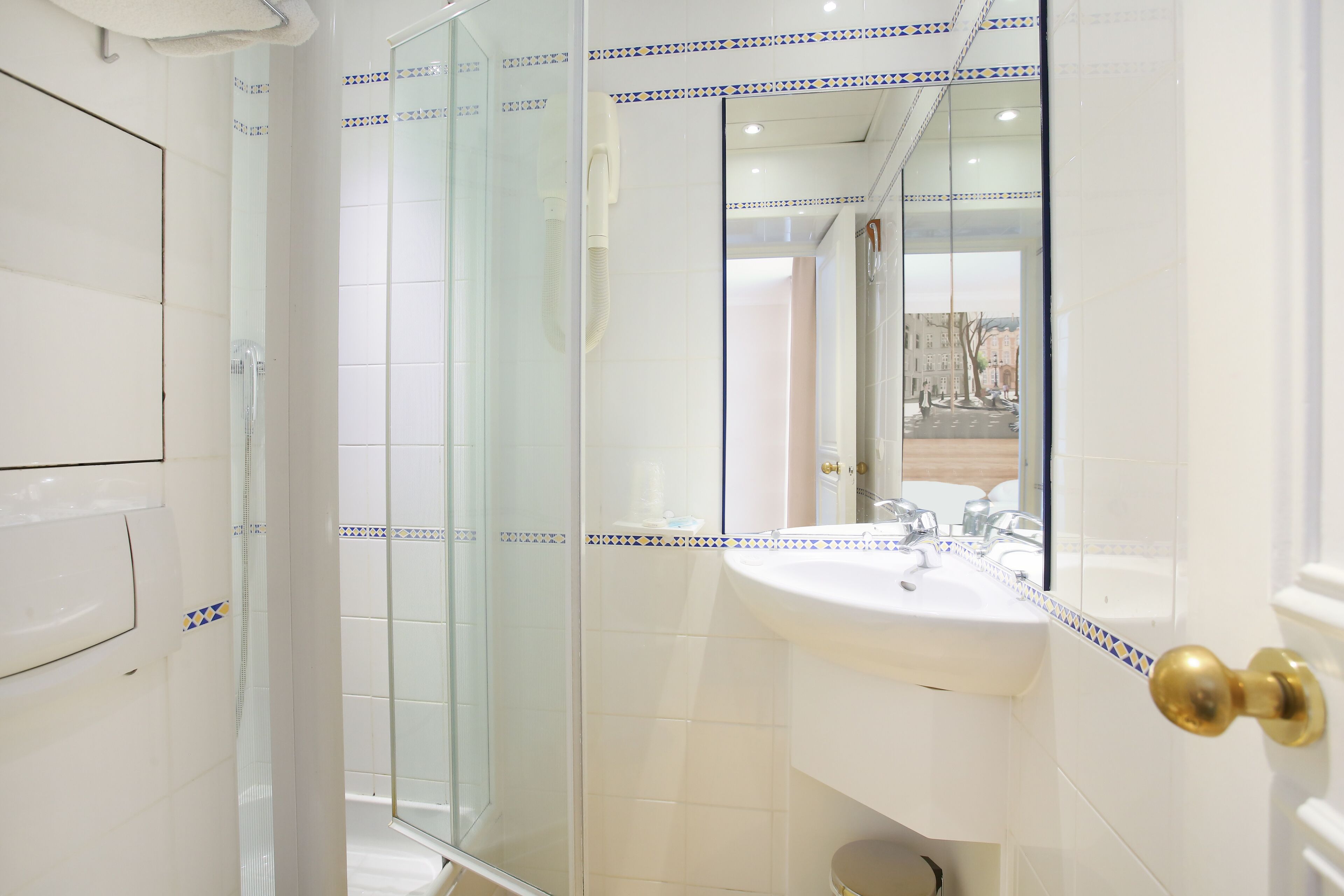 Un baño con cabina de ducha de vidrio, un lavabo blanco y un espejo.