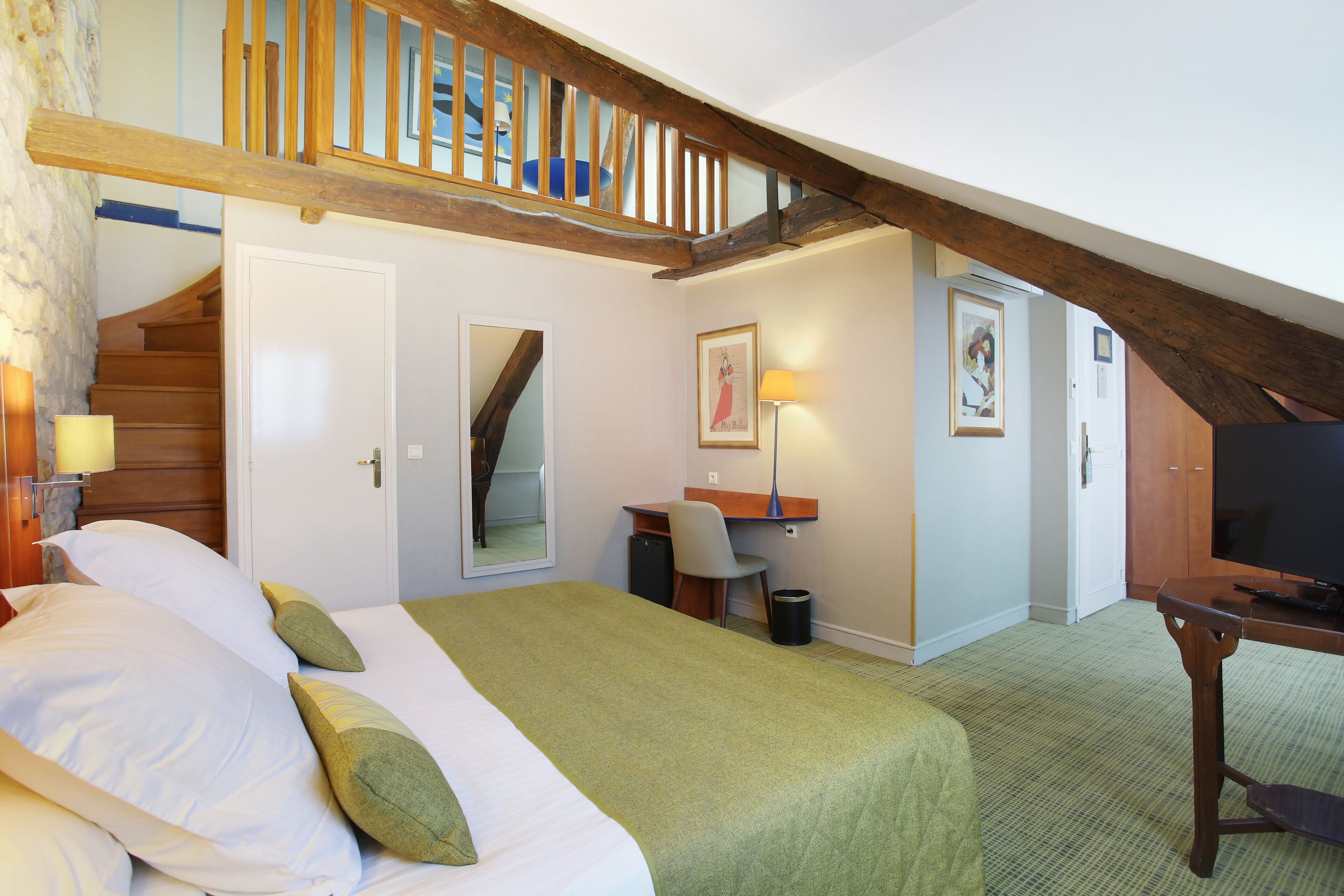 A bedroom with a bed, a desk, a chair, a television, and a staircase.
